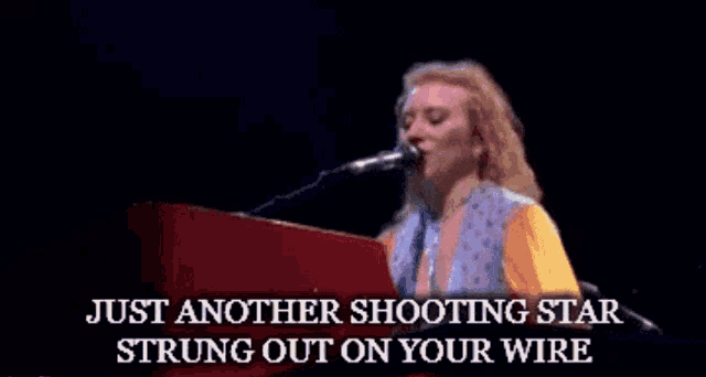 a woman singing into a microphone with the words just another shooting star strung out on your wire below her
