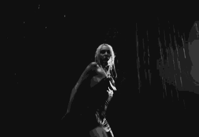 a woman in a bikini is dancing in the rain in a black and white photo .