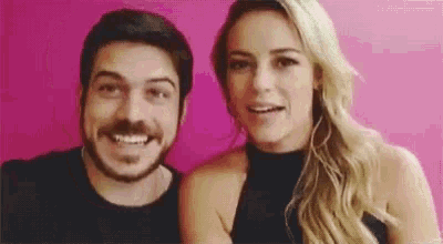 a man and a woman are posing for a picture in front of a pink background .
