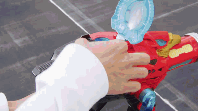 a person is holding a red toy gun with a blue circle on the top