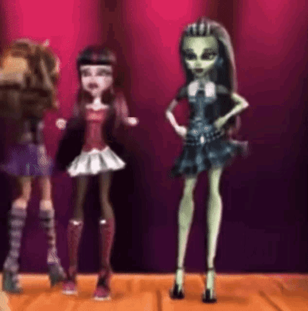 a group of monster high dolls are standing on a stage .