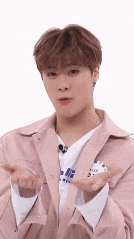 a young man in a pink jacket and white shirt is making a funny face with his hands outstretched .