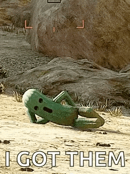 a green toy is laying on the ground in the desert with the words `` i got them '' .