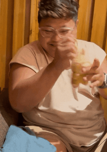 a man with glasses is eating a hamburger