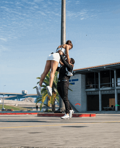a man is holding a woman up in the air in front of a building that says ' uc san diego '