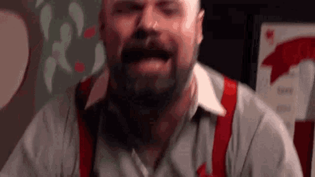 a man with a beard is wearing red suspenders and a nose ring .