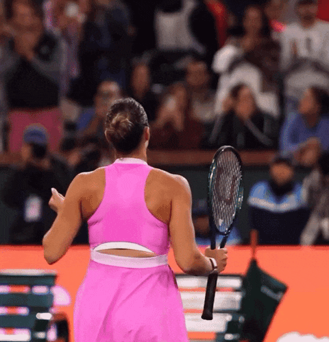 a woman in a pink dress holds a tennis racket