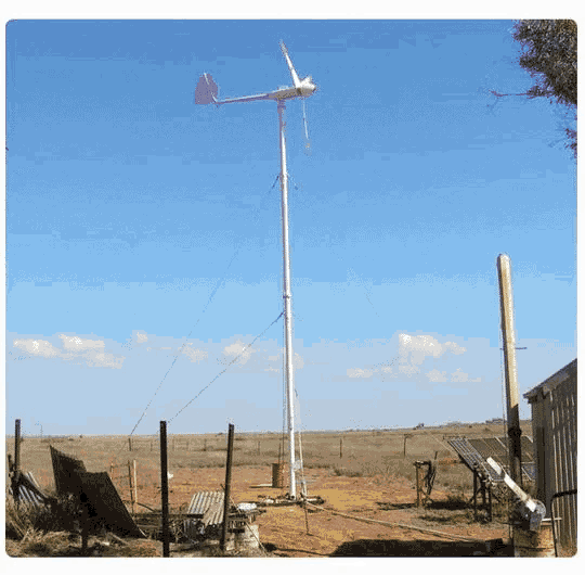 a wind turbine is sitting on top of a pole in the middle of a field