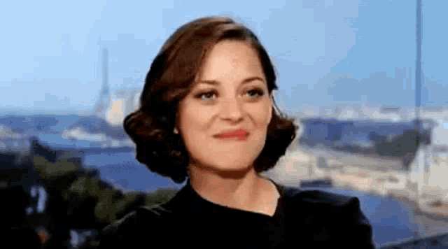 a woman in a black dress is making a funny face in front of a window .