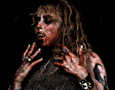 a woman with blood on her face is wearing a necklace with a cross on it
