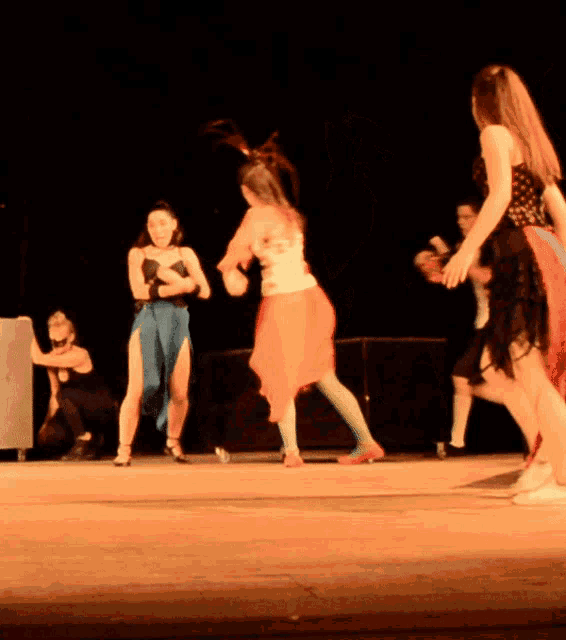 a woman in a red skirt is dancing on a stage with other women