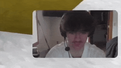 a young man wearing headphones and a microphone is sitting in front of a computer monitor .