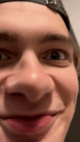 a close up of a man 's face with a hat on making a funny face