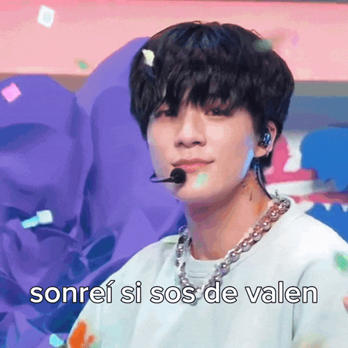 a young man wearing a microphone and a necklace with the words sonrei si sos de valen above him