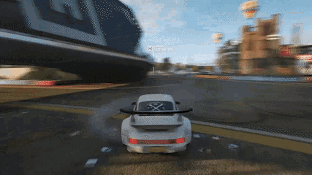 a white car is driving down a road with a sign in the background that says ' lotus '