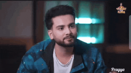 a man with a beard is wearing a blue jacket and a white shirt and is looking at the camera .