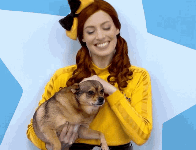 a woman in a yellow shirt holds a small brown dog in her arms
