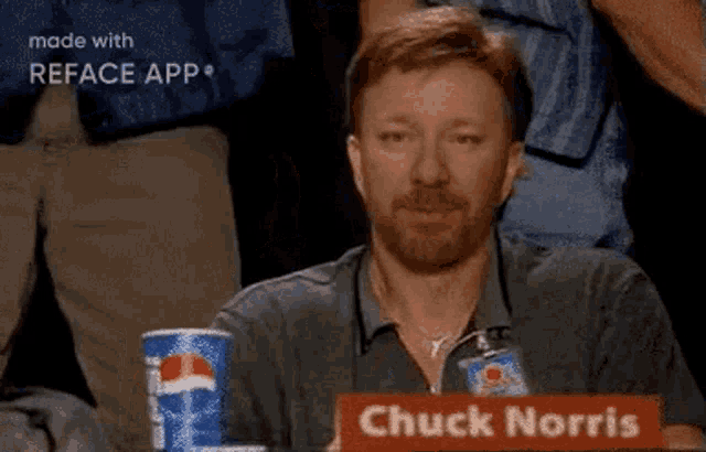 a man with a beard is sitting at a table with a pepsi can in front of him .