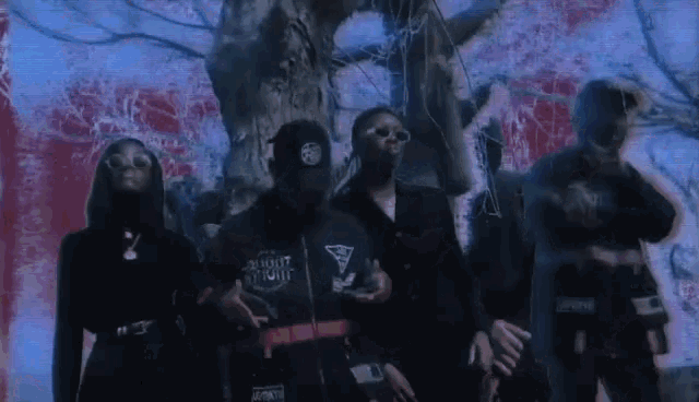 a group of people are standing in front of a tree .