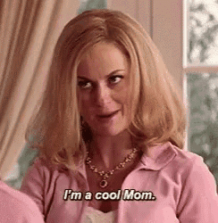 a woman is wearing a pink sweater and necklace and says `` i 'm a cool mom '' .
