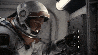 a man in a space suit is looking at a button on a wall