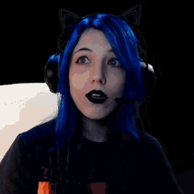 a girl with blue hair and black lipstick is wearing headphones and cat ears .