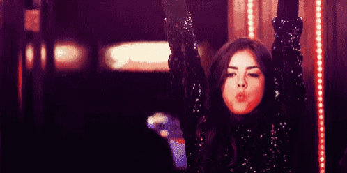 a woman in a sequined top is holding a cell phone in her hands and the words sextouuuu are behind her