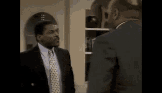 two men in suits and ties are standing next to each other .