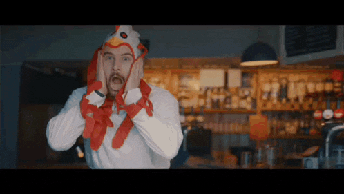 a man wearing a chicken hat is covering his ears