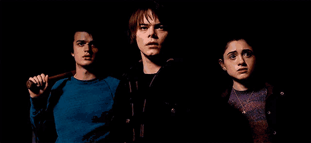 three people are standing next to each other in the dark .