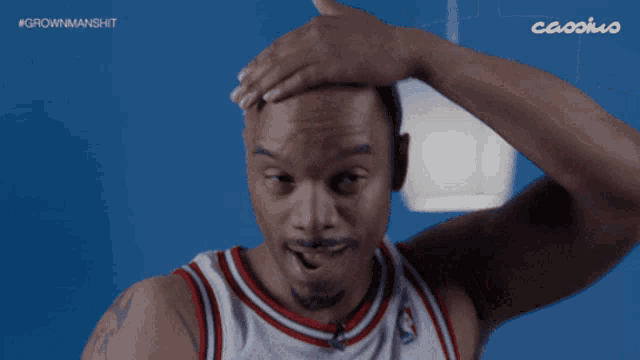 a man in a red white and blue jersey is shaving his head