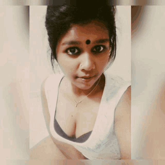 a woman with a bindi on her forehead is wearing a white tank top and black bra