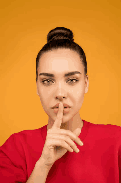 a woman in a red sweater holds her finger to her mouth