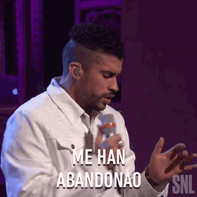 a man in a white jacket is singing into a microphone and says me han abandonado