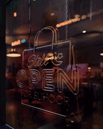 a neon sign that reads " this ramadan restaurants are open for suhoor "