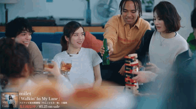 a group of people are sitting around a table playing jenga and drinking