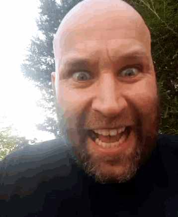 a bald man with a beard is smiling with his mouth wide open