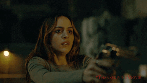 a woman with a surprised look on her face is holding a gun in a thanksgiving movie advertisement