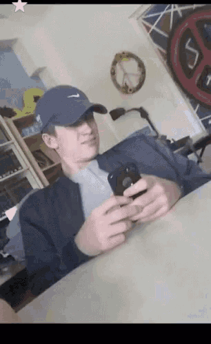 a man wearing a nike hat is sitting at a table looking at his cell phone