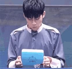 a man is holding a blue box with a heart on it .