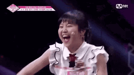 a girl is laughing on a stage while wearing a white shirt and a red tie .