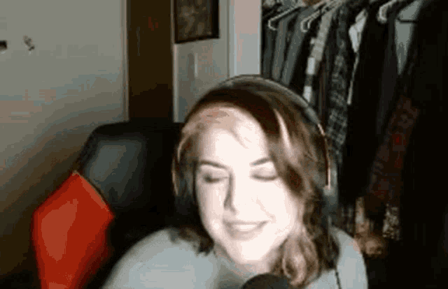 a woman wearing headphones and a headset is smiling in front of a microphone .