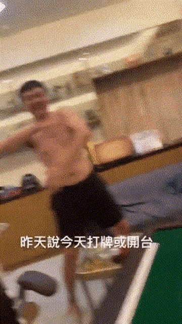 a man without a shirt is standing in a room with chinese writing on the bottom