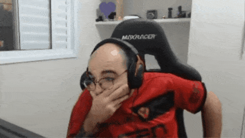 a man wearing headphones and a maxracer chair covering his mouth