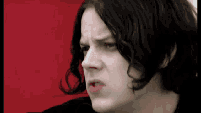 a close up of a person 's face with black hair and a red background