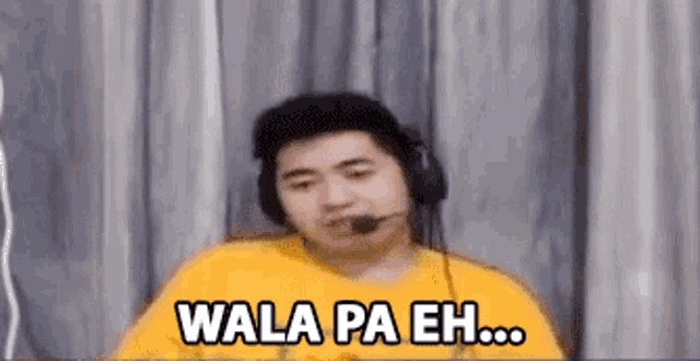 a man wearing headphones and a yellow shirt is making a funny face and saying `` wala pa eh '' .