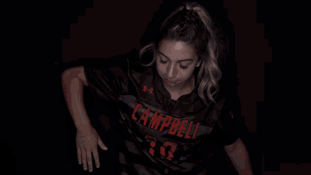 a woman in a campbell jersey is dancing in the dark