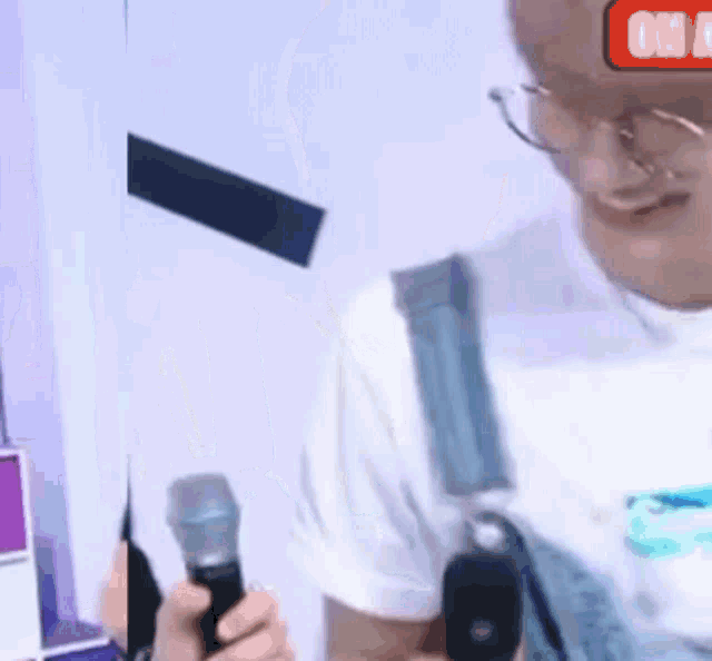 a man with glasses is holding a microphone in his hand .