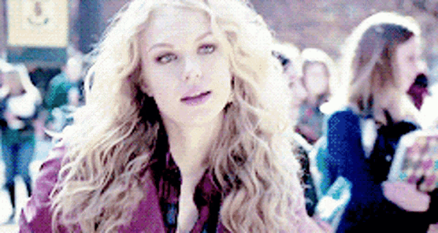 a woman with long blonde hair is standing in front of a crowd
