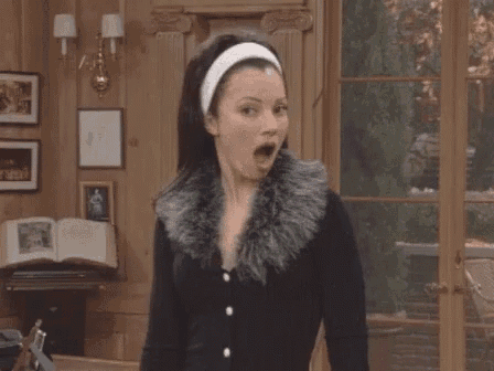 a woman is wearing a fur coat and a headband and making a surprised face .